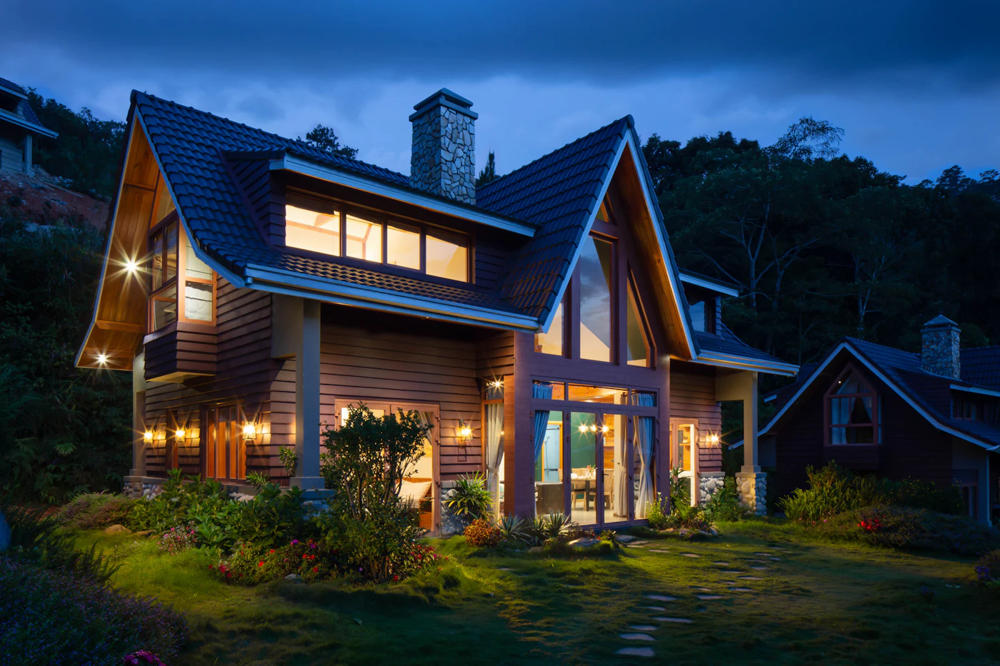 A home in the evening with warm exterior lighting across the garden