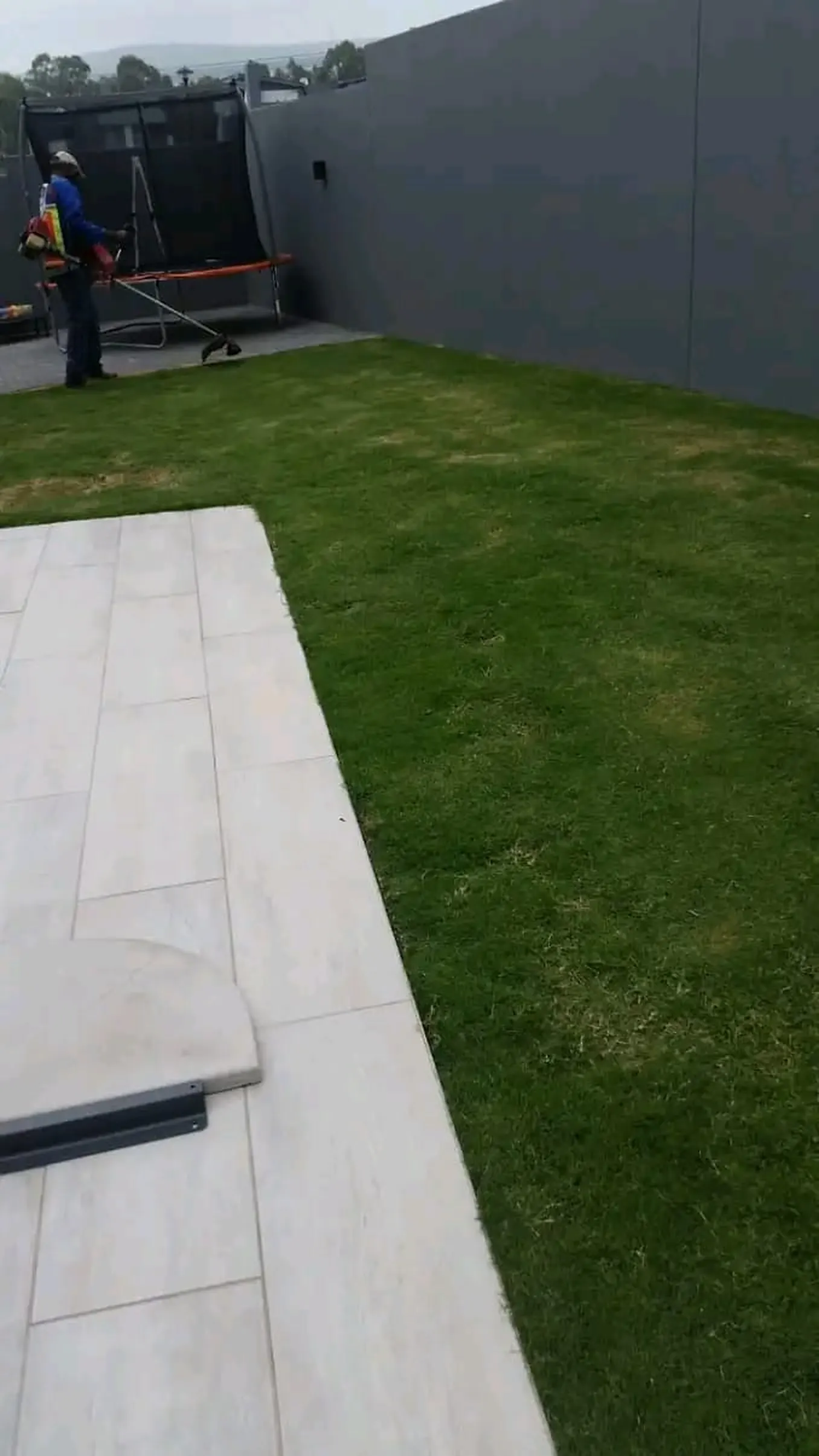 Large format paving slabs meeting a freshly laid lawn